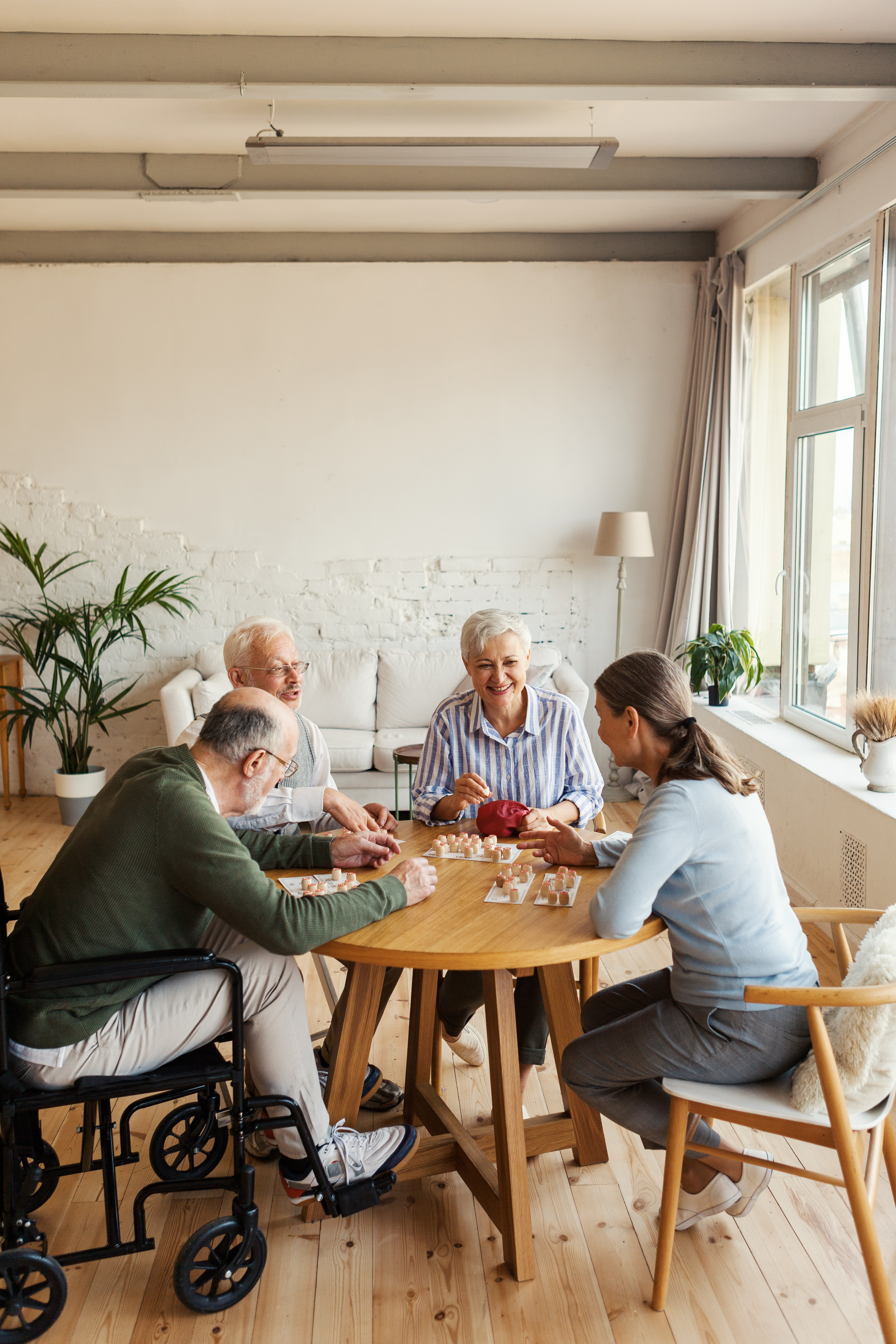 Group of four friendly senior people, two men and two women, sitting at table